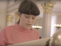 En pige læser op af en torahrulle inde i synagogen