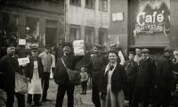 En samling af russiske jøder ude foran en café, nogen med aviser i hænderne 