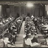 sort/hvid billede af studerende til eksamen i et stort rum ved hver deres bord
