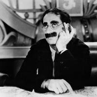 Groucho Marx med tykt overskæg og runde briller, som holde ren cigar