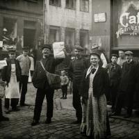 En samling af russiske jøder ude foran en café, nogen med aviser i hænderne 