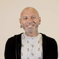 en mand der smiler med piercinger og tatoveringer i ansigtet
